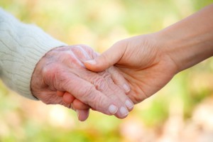 Senior and young holding hands outside