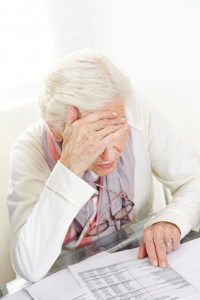 Unhappy senior woman looking at financial bill on the table